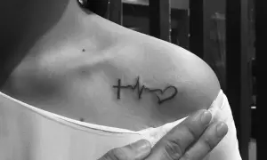 Tatuaż linia życia na ramieniu: krzyż, EKG i serce. Symbol wiary, życia i miłości.