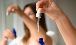 Kropla serum z butylen glicolem spada z pipety do niebieskiej buteleczki.