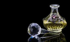 Elegancka buteleczka perfum z ozdobnym motywem kwiatowym i kryształowym korkiem. Zapach piżma unosi się, kusząc zmysły.