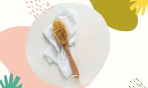Szczotka do szczotkowania twarzy leży na białym ręczniku. Idealny zestaw do domowego SPA.