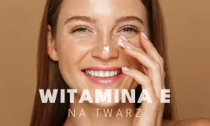 Uśmiechnięta kobieta z piegami aplikuje krem z witaminą E na twarz, dbając o swoją skórę.