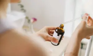 Kobieta aplikuje serum z pipetką na dłoń. Bezpieczny niacynamid w ciąży to klucz do promiennej cery.