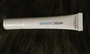 Biała tubka kremu OXYGEN CREAM na ciemnym, futrzanym tle.
