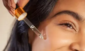 Kropla serum z pipetki zbliża się do skóry, ukazując subtelne retinol działanie.