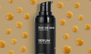 Czarny flakonik serum z alfa-arbutyną, otoczony kropelkami o bursztynowym kolorze.