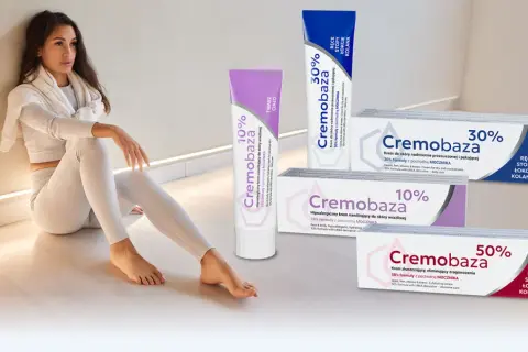 Kobieta w białym stroju siedzi obok tubek z kremami Cremobaza 10%, 30% i 50%.