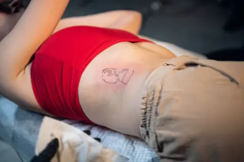 Nowy tatuaż na żebrach, przedstawiający abstrakcyjną postać.