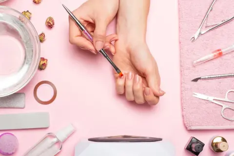 Narzędzia do manicure i dłonie przygotowujące się do zabiegu. Dowiedz się, jak zdjąć tipsy i uzyskać naturalny wygląd paznokci.