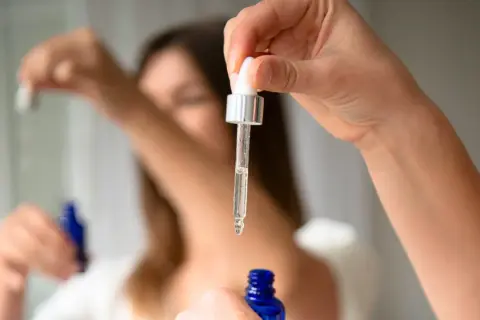Kropla serum z butylen glicolem spada z pipety do niebieskiej buteleczki.