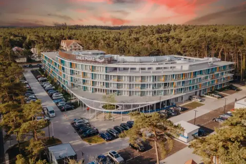Nowoczesny hotel Linea Mare otoczony lasem, z parkingiem pełnym samochodów. Warto sprawdzić opinie o Linea Mare przed rezerwacją.