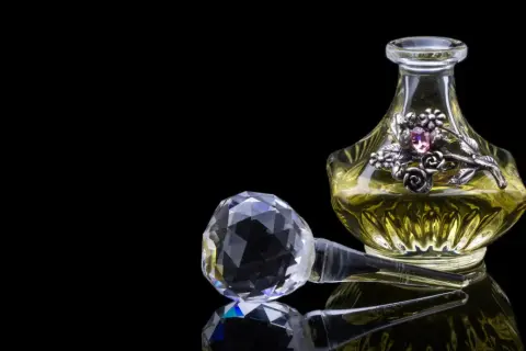 Elegancka buteleczka perfum z ozdobnym motywem kwiatowym i kryształowym korkiem. Zapach piżma unosi się, kusząc zmysły.