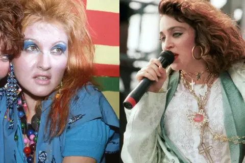 Ikony lat 80. w szalonych stylizacjach na imprezę: Cyndi Lauper z kolorowymi koralikami i Madonna z krzyżykami na szyi.