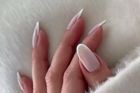 Dłonie z mlecznymi paznokciami w stylu french manicure, delikatne i eleganckie.