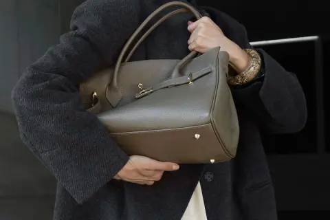 Elegancka, szara torebka z wysokiej jakości skóry, idealna dla miłośniczek luksusowych marki torebek. Złote okucia dodają jej blasku.