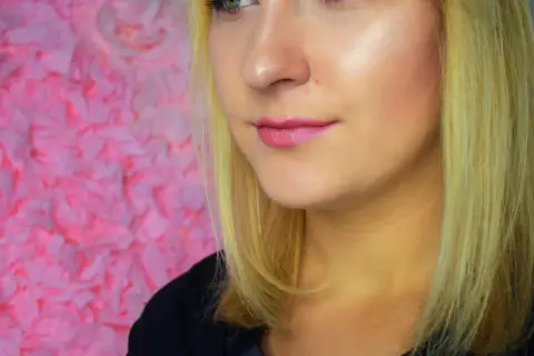 Uśmiechnięta blondynka z różowymi ustami, prezentująca rozświetlający podkład Mary Kay w różnych odcieniach.