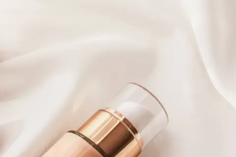Elegancka buteleczka kosmetyku na satynowym tle. Zastanawiasz się, czym się różni krem BB od CC?