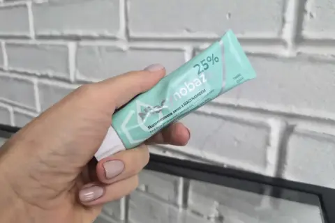 Dłoń trzyma tubkę serum Niacynobaza 25%. Wiele pozytywnych niacynobaza 25% opinie potwierdza jego skuteczność.