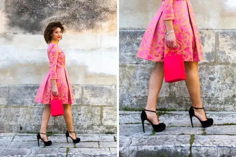 Elegancka kobieta w różowej sukience z złotym wzorem i czarnymi szpilkami. Idealne buty do różowej sukienki na specjalne okazje.