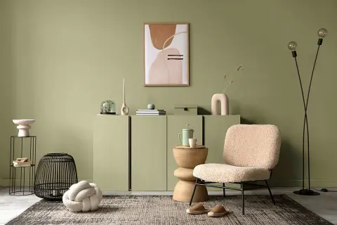 Przytulny salon w odcieniu **kolor sage**. Miękkie fotele, dekoracje i abstrakcyjny obraz tworzą spokojną atmosferę.