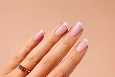 Dłoń z paznokciami w stylu french manicure. Idealny sposób, jak zrobić french, by wyglądać elegancko.