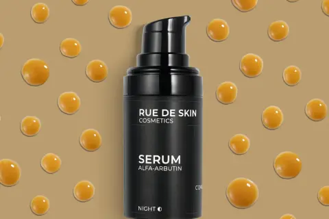Czarny flakonik serum z alfa-arbutyną, otoczony kropelkami o bursztynowym kolorze.