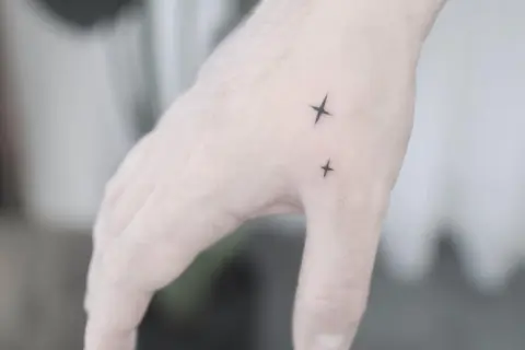 Dwa małe tatuaże męskie na rękę w kształcie gwiazdek.