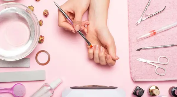 Narzędzia do manicure i dłonie przygotowujące się do zabiegu. Dowiedz się, jak zdjąć tipsy i uzyskać naturalny wygląd paznokci.