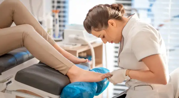 Profesjonalny pedicure co to? Kosmetyczka wykonuje zabieg pielęgnacji stóp, dbając o ich piękny wygląd.