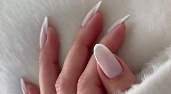 Dłonie z mlecznymi paznokciami w stylu french manicure, delikatne i eleganckie.