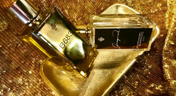 Dwa flakony perfum Marc Antoine Barrois na złotej, cekinowej tkaninie. Jeden flakon z napisem B683, drugi z nazwą "Ganymede".