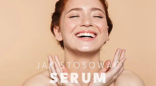 Uśmiechnięta kobieta z piegami, pokazująca, jak stosować serum do twarzy.