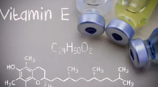 Wzór chemiczny witaminy E i fiolki z płynem. Witamina E jest ważna dla zdrowia.