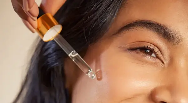 Kropla serum z pipetki zbliża się do skóry, ukazując subtelne retinol działanie.