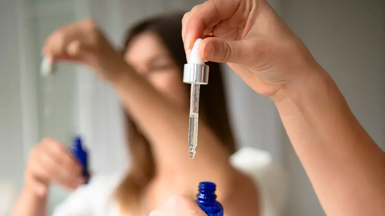 Kropla serum z butylen glicolem spada z pipety do niebieskiej buteleczki.