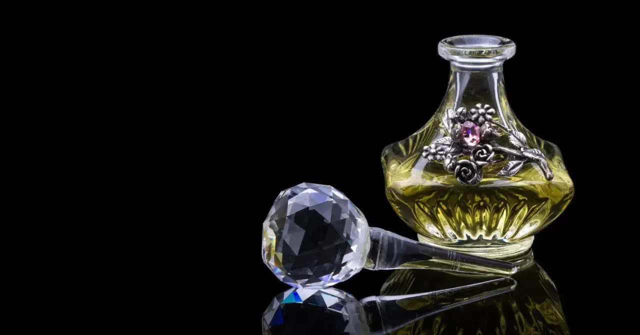 Elegancka buteleczka perfum z ozdobnym motywem kwiatowym i kryształowym korkiem. Zapach piżma unosi się, kusząc zmysły.