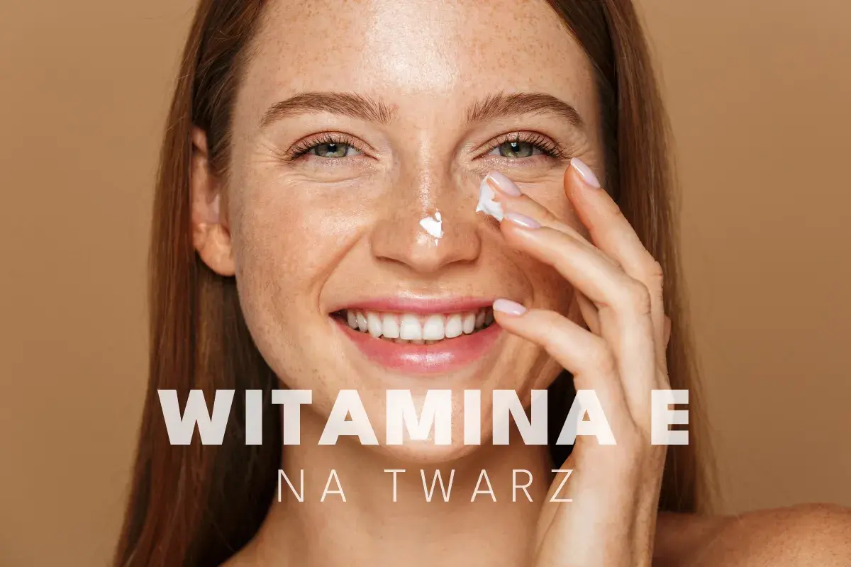 Uśmiechnięta kobieta z piegami aplikuje krem z witaminą E na twarz, dbając o swoją skórę.