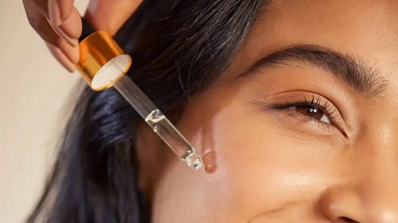 Kropla serum z pipetki zbliża się do skóry, ukazując subtelne retinol działanie.