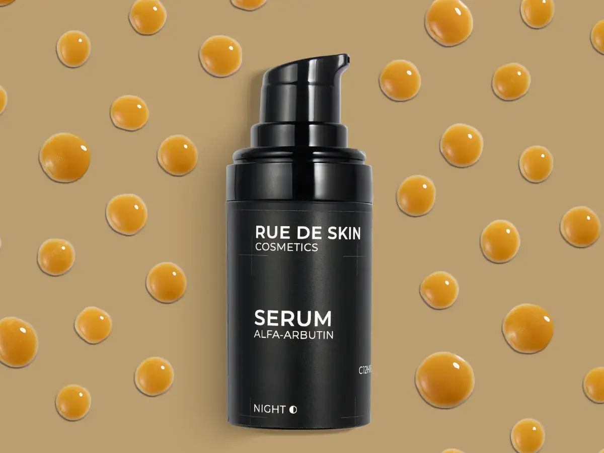 Czarny flakonik serum z alfa-arbutyną, otoczony kropelkami o bursztynowym kolorze.