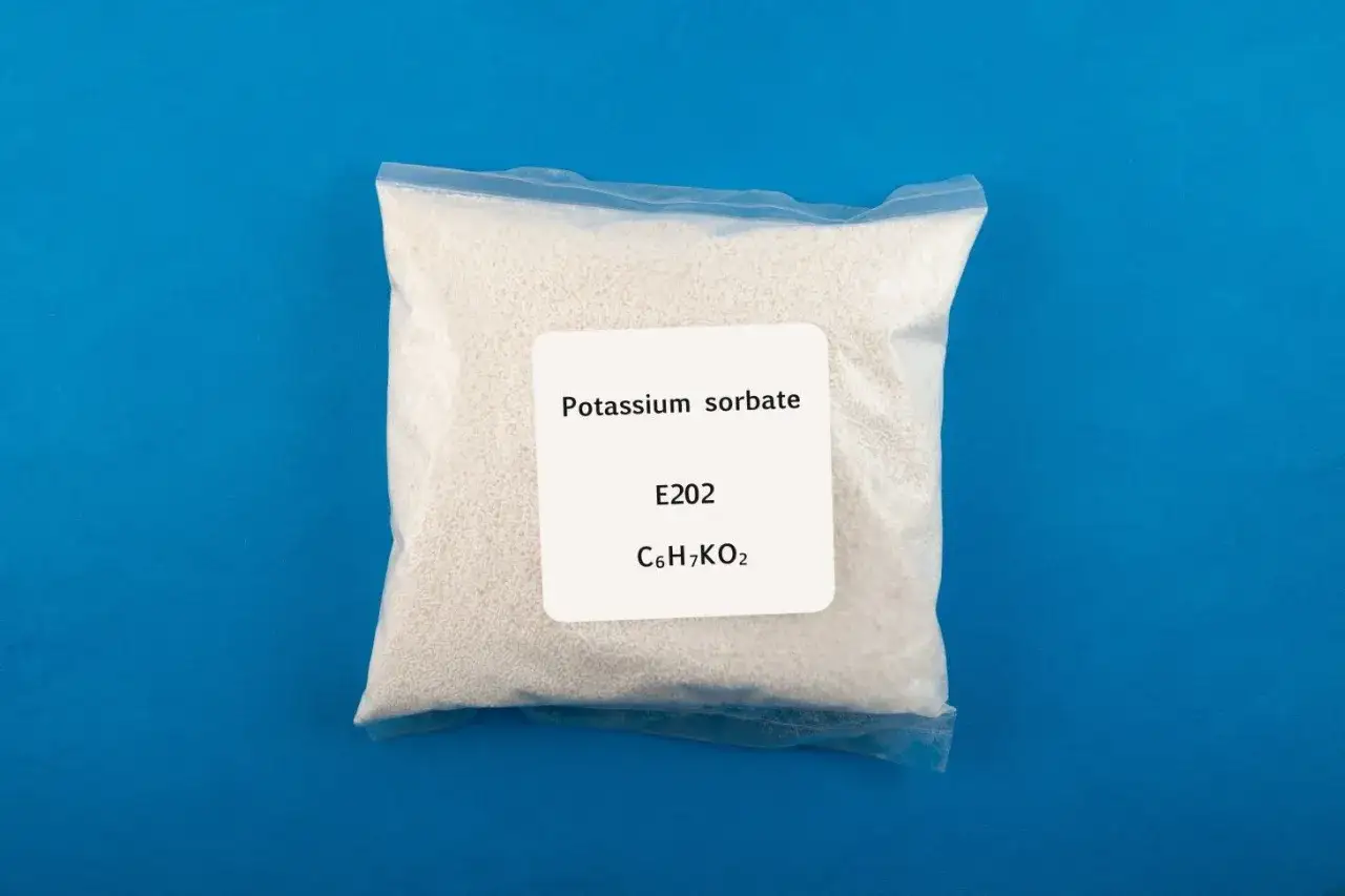 Biały proszek w przezroczystej torebce, z etykietą: Potassium sorbate, E202, C6H7KO2.