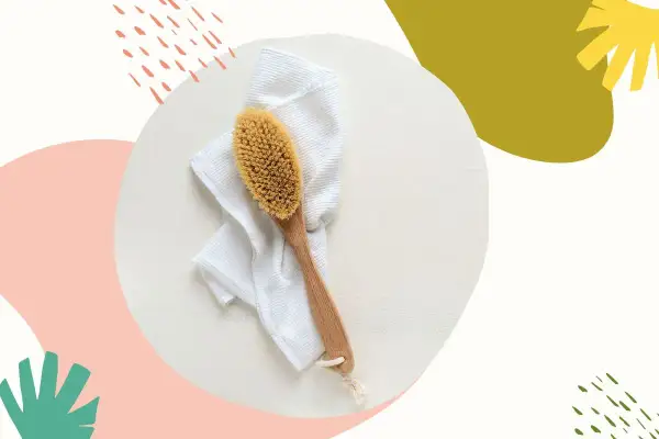 Szczotka do szczotkowania twarzy leży na białym ręczniku. Idealny zestaw do domowego SPA.