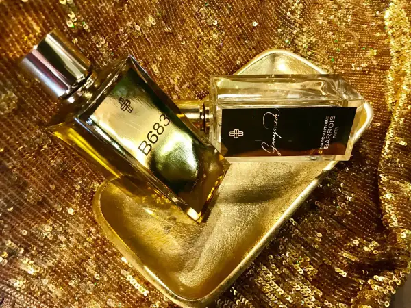 Dwa flakony perfum Marc Antoine Barrois na złotej, cekinowej tkaninie. Jeden flakon z napisem B683, drugi z nazwą "Ganymede".
