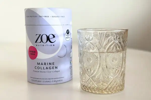 Opakowanie Zoe Nutrition Marine Collagen o smaku malinowym obok szklanki. Czy warto kupić? Sprawdź collagen drink dr max opinie.