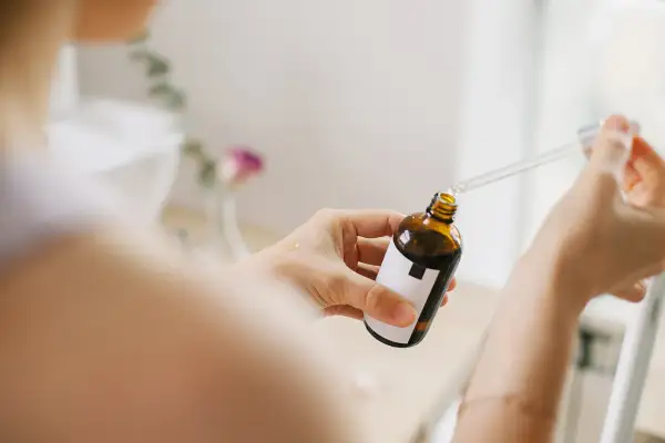 Kobieta aplikuje serum z pipetką na dłoń. Bezpieczny niacynamid w ciąży to klucz do promiennej cery.