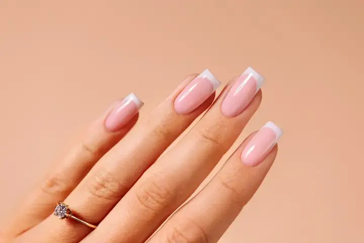 Dłoń z paznokciami w stylu french manicure. Idealny sposób, jak zrobić french, by wyglądać elegancko.